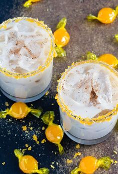 two glasses filled with drinks sitting on top of a table next to orange peels