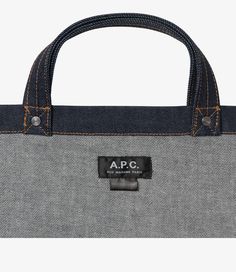 A.P.C. tote bag.  - Unisex model. - Two large handles. May be carried by hand or on shoulder. - Exterior pocket embroidered with caramel-colored A.P.C. logo. - Interior pocket. - Rivets engraved A.P.C. - Caramel-colored topstitching. Faux Leather Bag, Indigo Denim, Exclusive Clothing, C Logo, Mini Tote Bag, Backpack Tote Bag, Caramel Color, Scarf Jewelry, Mini Tote