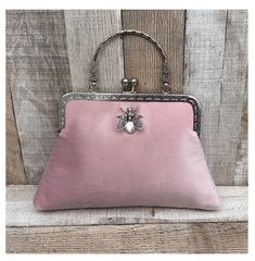 Stunning, handmade, blush pink velvet purse bag with bee detail. The lining is made with a beautiful cotton fabric. Use it as a classic clutch or attach the shoulder strap to wear over your shoulder or as a crossbody. - Silver colour Chain strap (detachable) - Silver colour Metal Top handle ( not detachable) - H:19cm x W:29cm x D:4cm approximately - Metal clasp: H:6.5cm x W:20cm - Top handle: H:8.5cm The pattern of the lining inside of the bag may vary. But don't worry, I always make sure the li Blush Rectangular Bag For Parties, Pink Rectangular Clutch With Detachable Handle, Rectangular Pink Clutch With Detachable Handle, Blush Rectangular Party Bag, Rectangular Blush Party Bag, Pink Evening Bag With Detachable Handle For Formal Occasions, Pink Evening Bag With Detachable Handle For Formal Events, Pink Top Handle Clutch For Evening, Elegant Pink Clutch Bag