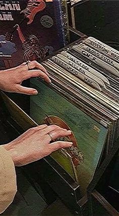 a person's hand reaching for an album in a record player's case