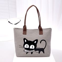 a black cat is on the side of a gray tote bag