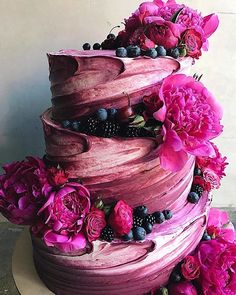 a pink cake with flowers and berries on top