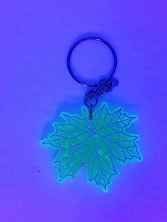 a glowing green leaf shaped keychain on a purple background