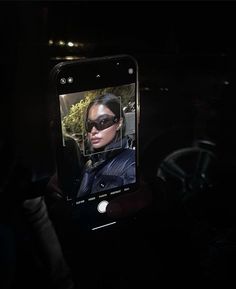 a cell phone with an image of a woman in sunglasses on it's screen