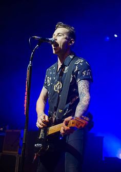 a man singing into a microphone while holding a guitar in front of him on stage