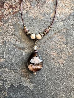 This beautiful Cherry Blossom Agate gemstone necklace is hung on a brown leather cord with natural wood beads, czech rustic glass beads and bronze metal accents. Light weight, simple and unique. Quality gift idea or something special for yourself. *I do not like it when I wear a necklace and my clasp eventually shifts to the front. This necklace, the clasp will stay in the back.  *The other necklace in the photos should be in my shop unless sold.  Details:  Cherry Bloosom Agate oval gemstone Natural wood beads 6mm Natural golden rutilated quartz faceted gemstone 4mm Glass beads Bronze metal spacers and beads Brown distressed genuine leather cord 1mm (thin) Bronze lobster clasp Length: leather cord is 16", pendant length is 1 1/2". I can add a 2" extension chain to make necklace 18", put in Nature-inspired Brown Jewelry With Gemstone Beads, Rustic Brown Agate Jewelry, Rustic Adjustable Necklace With Natural Stones, Brown Natural Stones Necklace For Festival, Festival Brown Jewelry With Natural Stones, Rustic Brown Gemstone Bead Necklace, Rustic Brown Gemstone Bead Necklaces, Rustic Brown Pendant Jewelry, Rustic Brown Healing Necklace