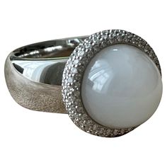 This fabulous Cocktail Ring in 18 K white Gold features a sugarloaf Moonstone Cabochon weighing 8.50 ct and is modernly surrounded by brilliant cut Diamonds with a total weight of 0.80 ct, G color, vs clarity. It is signed Gübelin Lucerne, Switzerland. Solid white Gold. The ring is currently size 55/15 (US ring size 7 1/2 ) but can be resized easily. Masterfully handcrafted piece! Authenticity and money back is guaranteed. For any enquires, please contact the seller through the message center. Luxury Diamond Gemstones With Cabochon Cut, Luxury Diamond Cabochon Gemstones, Luxury Round Gemstones With Diamond Accents, Luxury White Gold Polished Gemstones, Modern Polished Finish Gemstones, Luxury White Gold Diamond Ring With Gemstone Accents, White Diamond Gemstones In Fine Jewelry Style, Fine Jewelry White Diamond Gemstones, Modern White Gold Diamond Ring With Gemstone