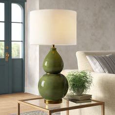 a green lamp sitting on top of a glass table next to a couch and chair