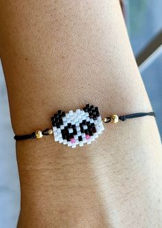 a woman wearing a black and white beaded bracelet with a panda face on it