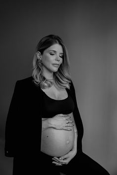 a pregnant woman sitting in a chair with her hands on her belly