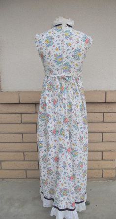 "Vintage 1970's summer dress! Sweetest white eyelet fabric dress with a red, yellow, lavender and green floral and fruit print. Eyelet fabric has small holes edged in machine embroidery. It has an empire waist with attached same fabric belt. The high neckline has a double row of eyelet lace trimmed in black grosgrain ribbon. The bottom is hemmed in a large row of eyelet lace trimmed in matching grosgrain ribbon. Back metal zipper. This adorable dress was custom made. Fabric feels like a cotton/p Sleeveless Cotton Vintage Dress With Floral Print, Vintage White Sleeveless Sundress, White Sleeveless Vintage Sundress, Multicolor Vintage Summer Dress, Vintage White Sundress With Floral Print, Vintage White Floral Print Sundress, Vintage Floral Print Sundress For Daywear, White Vintage Floral Print Sundress, White Cotton Vintage Summer Dress