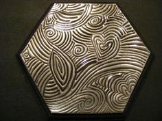 a silver plate with swirls and hearts in the center on a black table top