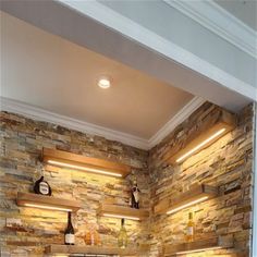 a kitchen with stone walls and wooden shelves on the wall, along with an oven