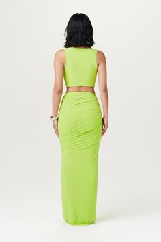 a woman in a lime green dress with her back to the camera, looking down