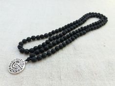 Mala made of 6mm Black Lava beads and OM simbol. This beautiful mala will be a pleasure to recite your mantras with, meditate with, or wear as a beautiful necklace. 108 beads (no knots). It measures approximately 26 inches in total length. Lava Stone is a grounding stone. It gives us strength and courage, allowing us stability through times of change. A calming stone, it is very useful in dissipating anger. Lava Stone enhances fertility. All our jewels arrive carefully packaged in a gift box rea Spiritual Black Beaded Necklaces, Spiritual Black Beaded Necklaces For Meditation, Spiritual Black Beads Mala For Meditation, Handmade Black Mala For Meditation, Silver Mala With 108 Beads For Meditation, Spiritual Black Beads Necklace For Meditation, Lava Stone Jewelry For Meditation, Black Beaded Mala For Meditation, Black Beads Mala For Meditation