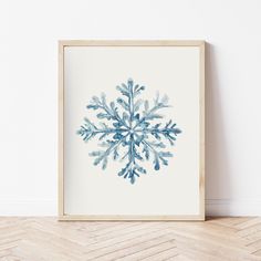 a blue and white snowflake is displayed in a wooden frame on the floor