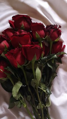 a bunch of red roses laying on top of a white sheet