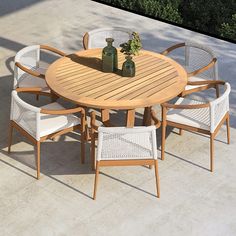 a wooden table with white wicker chairs and vases sitting on top of it