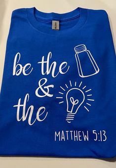 a blue t - shirt with the words be the and the light bulb printed on it