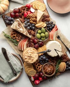 an assortment of cheeses, crackers and fruit on a platter