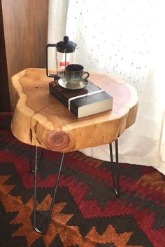 a wooden table with some books and a coffee pot on it, in front of a window