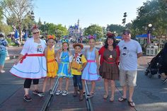 a group of people standing next to each other in front of a train track at disney world