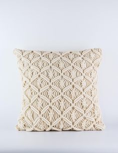 the crochet pillow is made from white yarn and has a decorative pattern on it