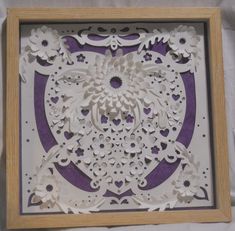 an intricate paper cut design in a wooden frame