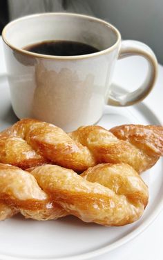 a white plate topped with donuts next to a cup of coffee