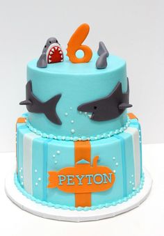 a birthday cake with two dolphins and an orange number on the bottom tier is decorated in blue icing