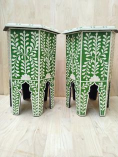 pair of green and white painted side tables on wooden floor with plant motif inlays