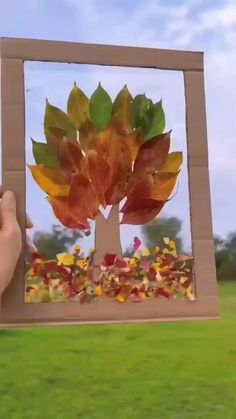 a person holding up a cardboard box with leaves on it in front of a grassy field