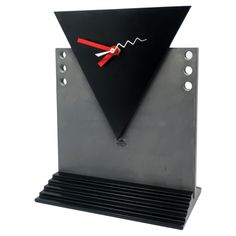 a black and silver clock with red hands on it's face that is shaped like a triangle