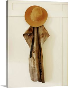 a hat and coat hang on the wall in front of a white door with an open jacket hanging from it