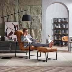 a man sitting in a chair with his feet up on the floor while talking on a cell phone