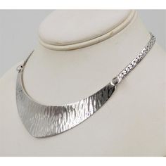 This is part of Chairish’s Costume Jewelry assortment.  Rhodium plated textured bib necklace with spring ring clasp. Unmarked but matching cuff (sold separately) is marked. Circa 1976 or 77 based on similarly styled bracelets and necklaces advertised in those years. Measures: 6 inches long by 4 1/4 inches wide. Center; 1 inch. Excellent condition.  Color: silver  Please reference the measurements noted in the description above for the best approximate dimensions. Please reach out to the seller u Elegant Hand Forged Choker Necklaces, Formal Metal Necklace With Polished Finish, Metal Jewelry With Polished Finish For Anniversary, Elegant Hammered Choker Jewelry, Modern Necklace With Sterling Silver Clasp, Hammered Metal Jewelry For Formal Occasions, Formal Hammered Metal Jewelry, Formal Metal Necklace With Oxidized Finish, Formal Metal Necklaces With Sterling Silver Clasp