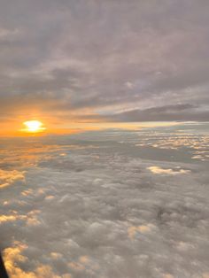 the sun is setting over some clouds from an airplane