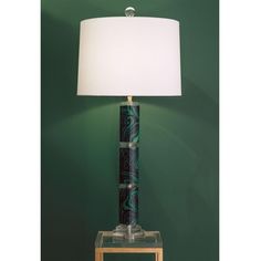 a lamp that is sitting on top of a wooden table next to a green wall