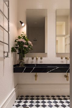 a bathroom with black and white checkered flooring next to a wall mounted mirror