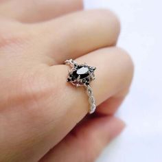 a woman's hand wearing a ring with black and white stones on the side