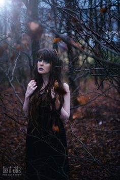 a woman with long hair standing in the woods