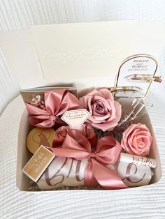 pink roses in a gift box with personalized items on the side and an envelope