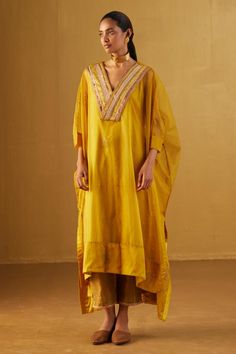 Ochre kaftan with floral hand block prints, lace trims and zari work on neckline. Comes with under slip and gold tissue cigarette pant.
Components: 2
Pattern: Hand Block Print
Type Of Work: Floral
Neckline: V Neck
Sleeve Type: Batwing
Fabric: Kurta: Organza, Slip: Satin, Pant: Handloom Tissue
Color: Yellow
Other Details: 
Lace trims
2 side pockets on pant
Partially elasticated waistband
Length:
Kaftan front: 45 inches
Kaftan back: 50 inches
Pant: 36 inches
Model height: 5ft 9inches, wearing size Silk Pant, Tie Dye Tunics, Palazzo Set, Pattern Embroidery, Top Pants Set, Patch Work, Silk Embroidery, Print Crop Tops, Embroidered Jacket