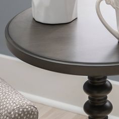 a coffee cup sitting on top of a wooden table next to a white vase and chair