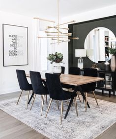 a dining room table with black chairs and a white rug on the floor in front of it