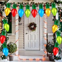 a decorated front porch with christmas lights and decorations on the door, potted plants and wreath