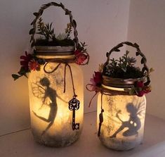 two mason jars with flowers and fairy silhouettes on them