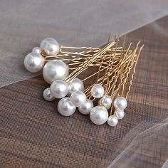 a bunch of white pearls sitting on top of a piece of cloth next to a hair pin