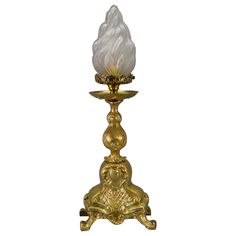 a golden candle holder with a white glass light on it's top and bottom