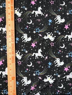 a black background with stars, unicorns and moon on it is next to a ruler